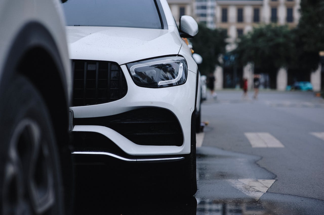 Close-up view of a sleek white car parked on a city street, reflecting urban style.