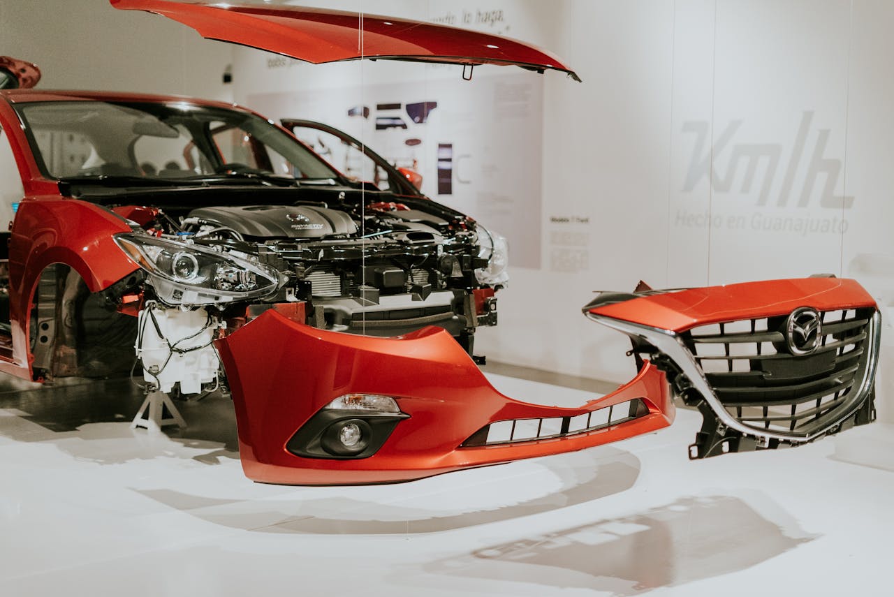who-we-are Explore a detailed view of a partially disassembled red Mazda 3 showcased at an auto exhibition.