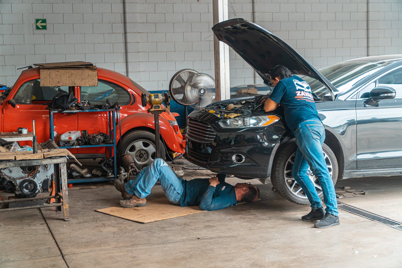 our-journey-02 Mechanics working in an automotive workshop, repairing cars and performing maintenance.